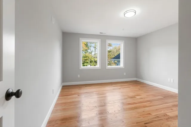 an empty room with wooden floor and windows