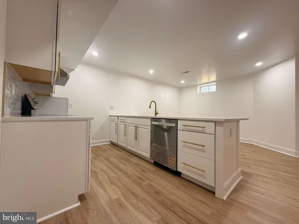 a view of an empty room with wooden floor and a bathroom