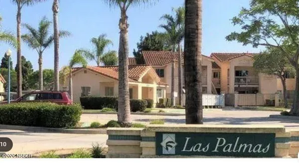 a view of a white house with a small yard and palm trees