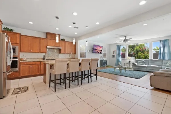 a kitchen with stainless steel appliances kitchen island granite countertop a stove a sink a dining table and chairs