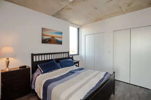 a bedroom with a bed and a lamp on dresser