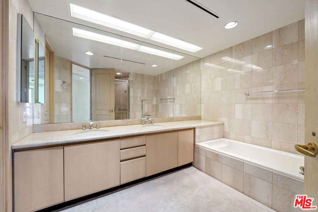 10490 Wilshire Boulevard, Unit 1402 Los Angeles, CA 90024 - Photo 13 of 67 a bathroom with a double vanity sink a large mirror and a bathtub