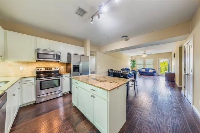 a kitchen with stainless steel appliances wooden floor and a refrigerator