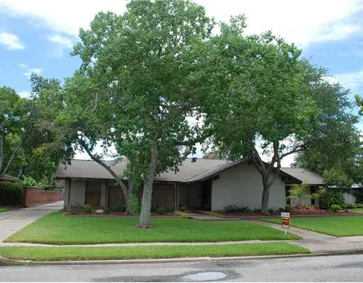 a front view of a house with a garden and trees