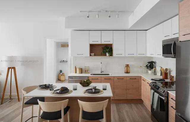 a kitchen with stainless steel appliances a white table and chairs in it