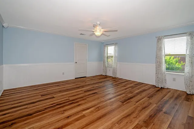 a view of empty room with wooden floor and fan