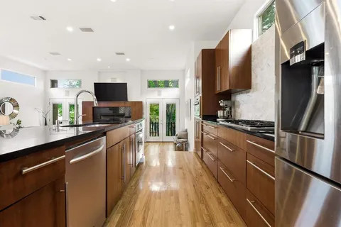 a kitchen with stainless steel appliances granite countertop a sink a stove and a wooden floors