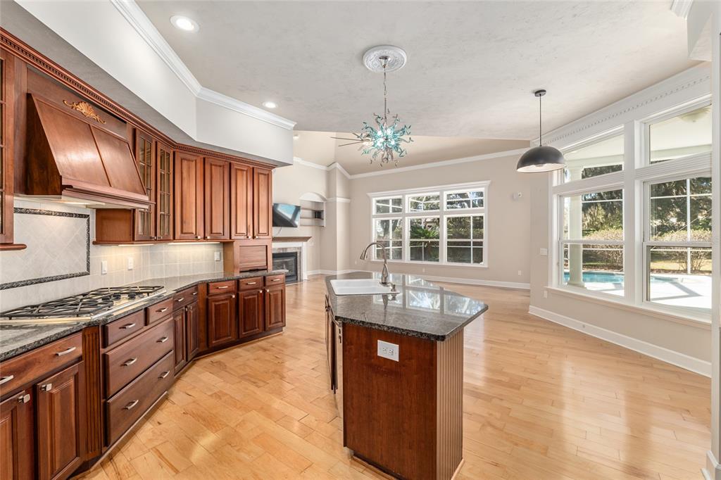 10614 Southwest 15th Lane Gainesville, FL 32607 - Photo 25 of 85 a kitchen with stainless steel appliances granite countertop a stove top oven a sink dishwasher a dining table and chairs with wooden floor