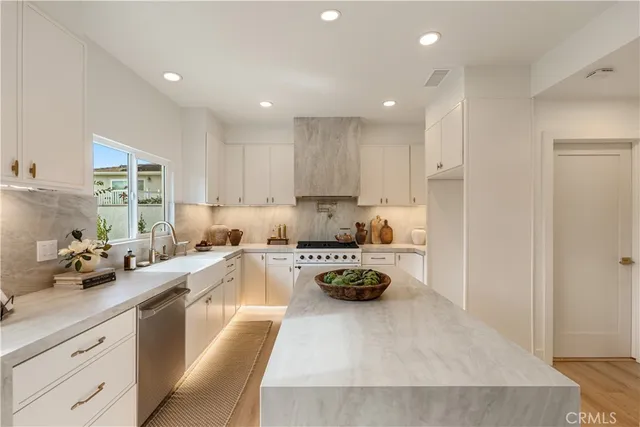 a kitchen with sink stove and white cabinets with wooden floor