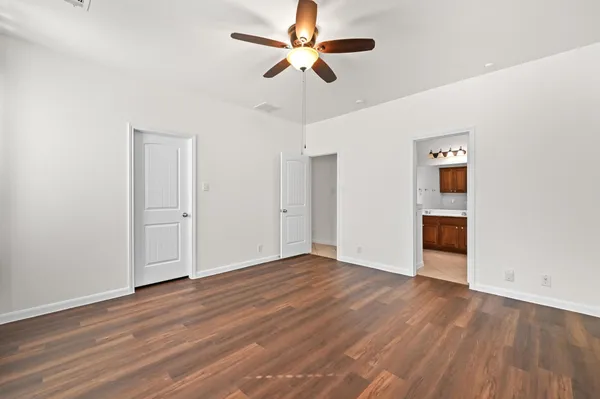 an empty room with wooden floor chandelier fan and entryway