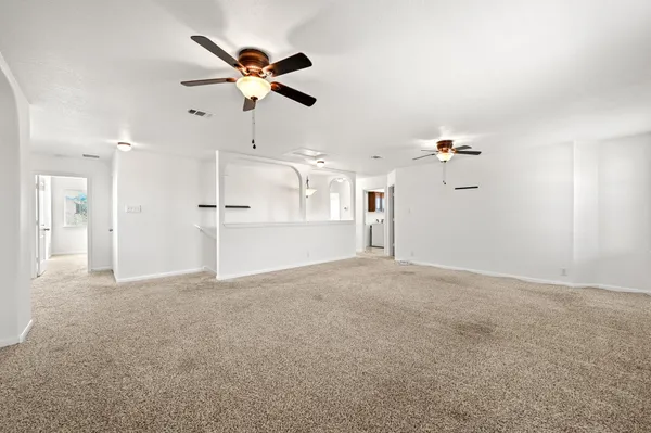 a view of a livingroom with a ceiling fan a kitchen space with a sink