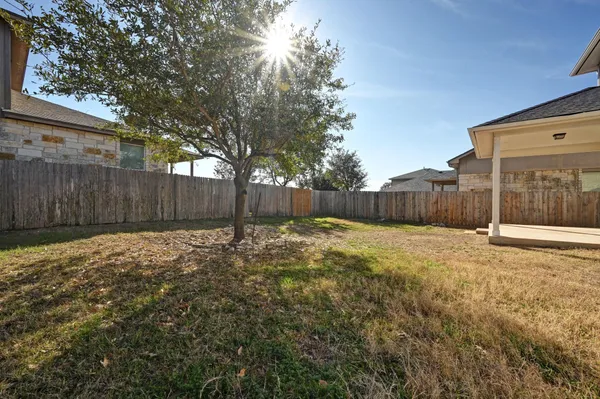 a view of a backyard with large trees and wooden fence