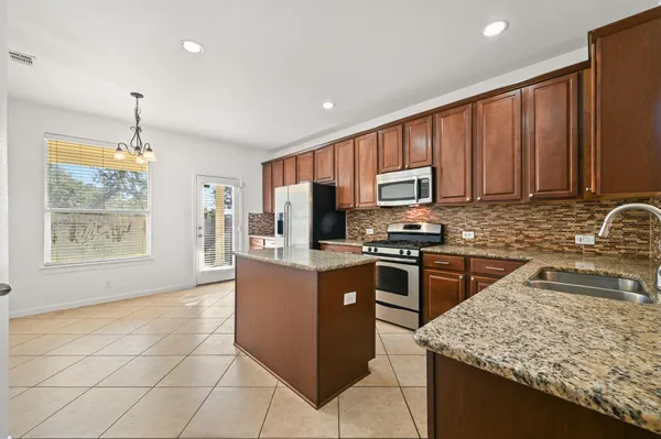 a kitchen with granite countertop a stove cabinets and refrigerator