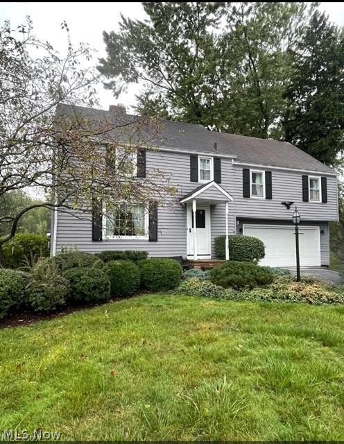 2800 Hillside Road Seven Hills, OH 44131 - Photo 2 of 18 Traditional-style residence featuring grey siding with black shutters, a covered entry porch, an attached two-car garage, and established front landscaping