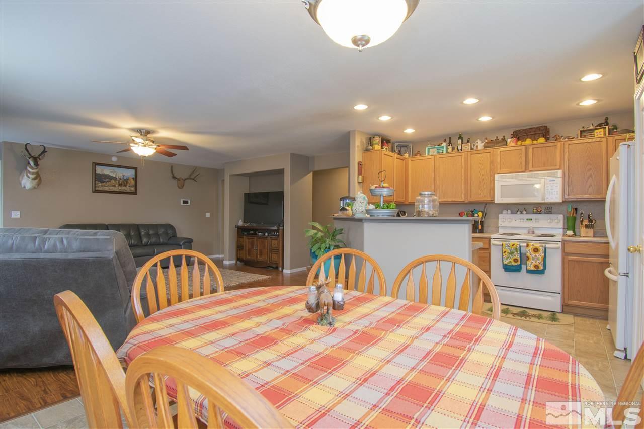 7749 Welsh Drive Reno, NV 89506 - Photo 6 of 25 a kitchen with stainless steel appliances granite countertop a dining table chairs and stove top oven with wooden floor