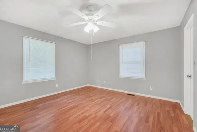 an empty room with wooden floor and windows