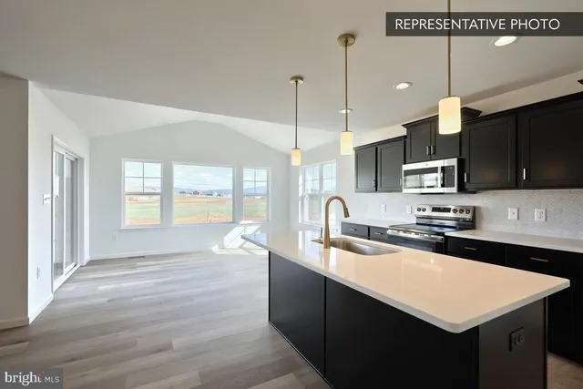 a kitchen with stainless steel appliances a sink a stove a refrigerator a center island and a wooden floor