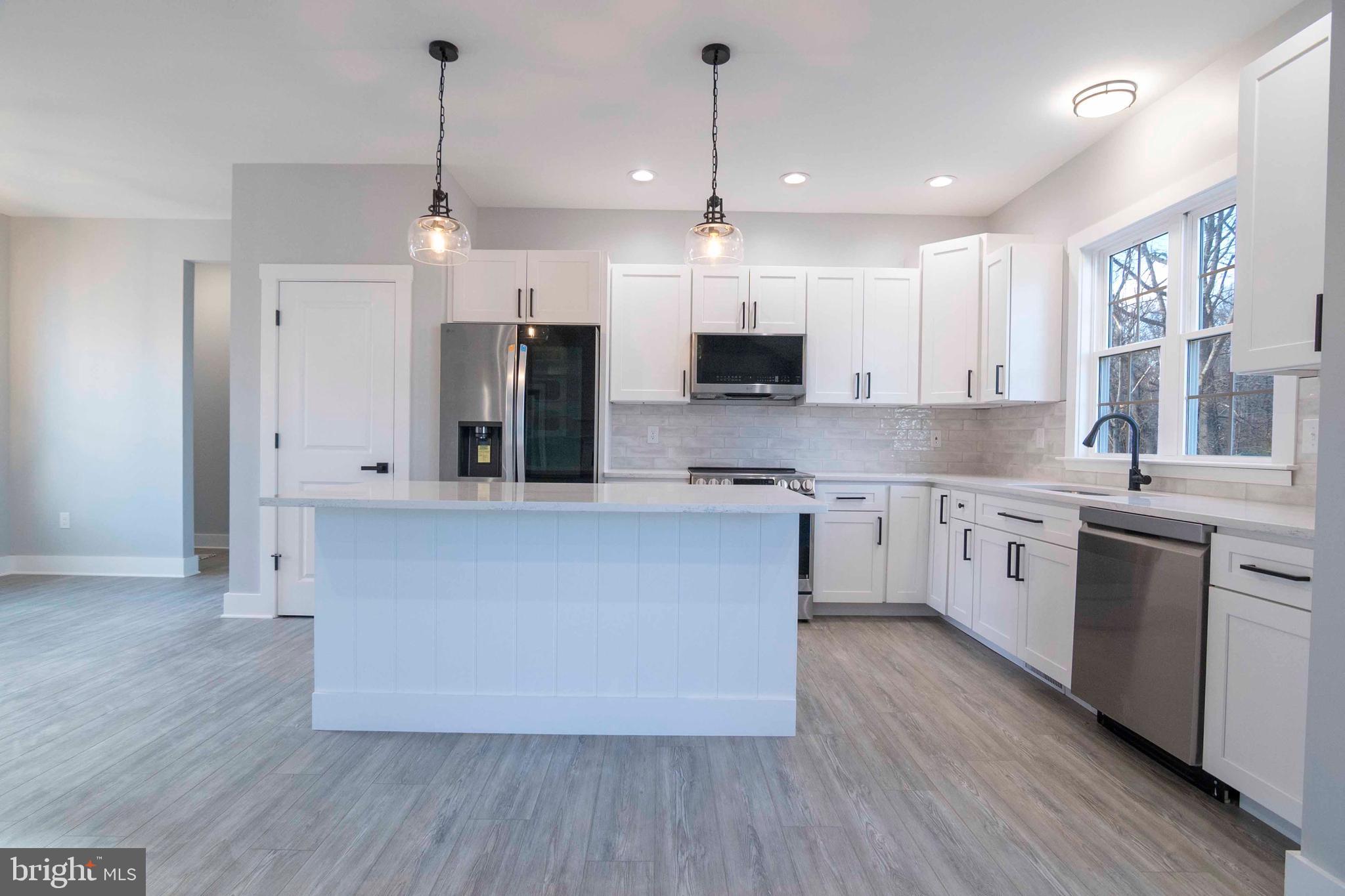 1633 Catlett Mountain Road Front Royal, VA 22630 - Photo 23 of 69 a large kitchen with stainless steel appliances kitchen island granite countertop a stove a sink dishwasher a refrigerator and white cabinets with wooden floor