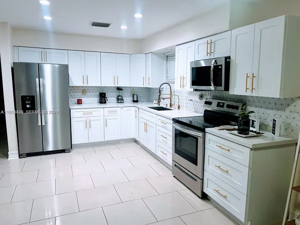 a kitchen with white cabinets stainless steel appliances and sink