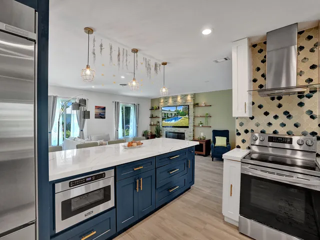 a living room with fireplace furniture kitchen view and a large window