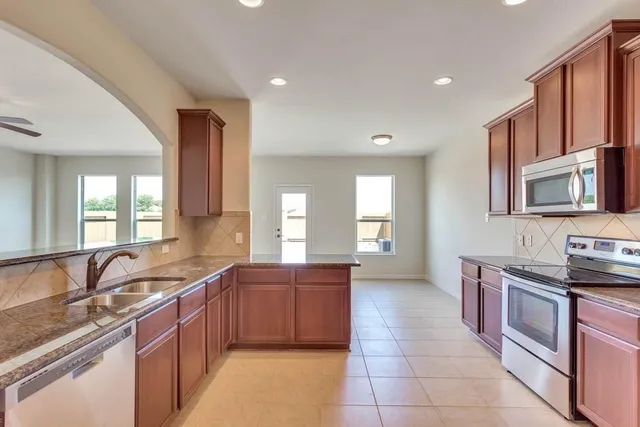a large kitchen with stainless steel appliances granite countertop a sink and a stove