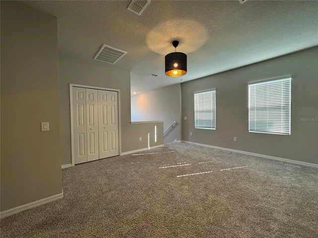 an empty room with windows and ceiling fan