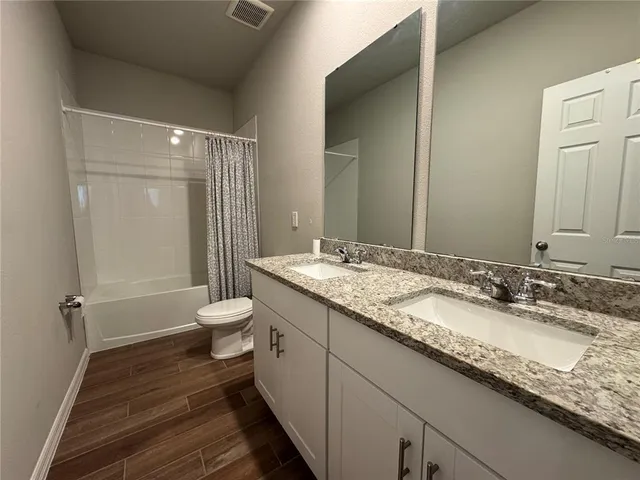 a bathroom with a granite countertop sink a toilet and a shower