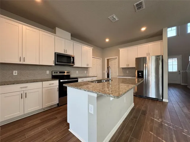 a large kitchen with stainless steel appliances granite countertop a stove a sink and a refrigerator
