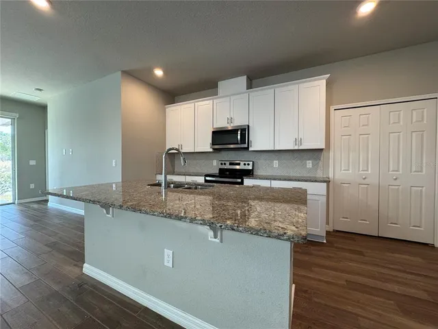 a kitchen with stainless steel appliances granite countertop a sink a stove a microwave a sink and cabinets