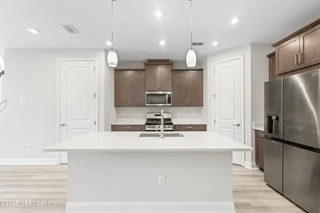 a kitchen with kitchen island a sink stainless steel appliances and cabinets