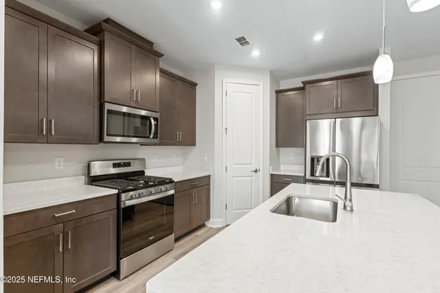 a kitchen with stainless steel appliances granite countertop a sink a stove and a refrigerator