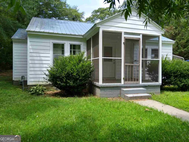 a view of a white house with a large window and garden