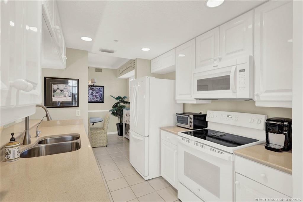 5700 Northeast Island Cove Way, Unit 4301 Stuart, FL 34996 - Photo 18 of 45 a kitchen with stainless steel appliances granite countertop a refrigerator sink and white cabinets