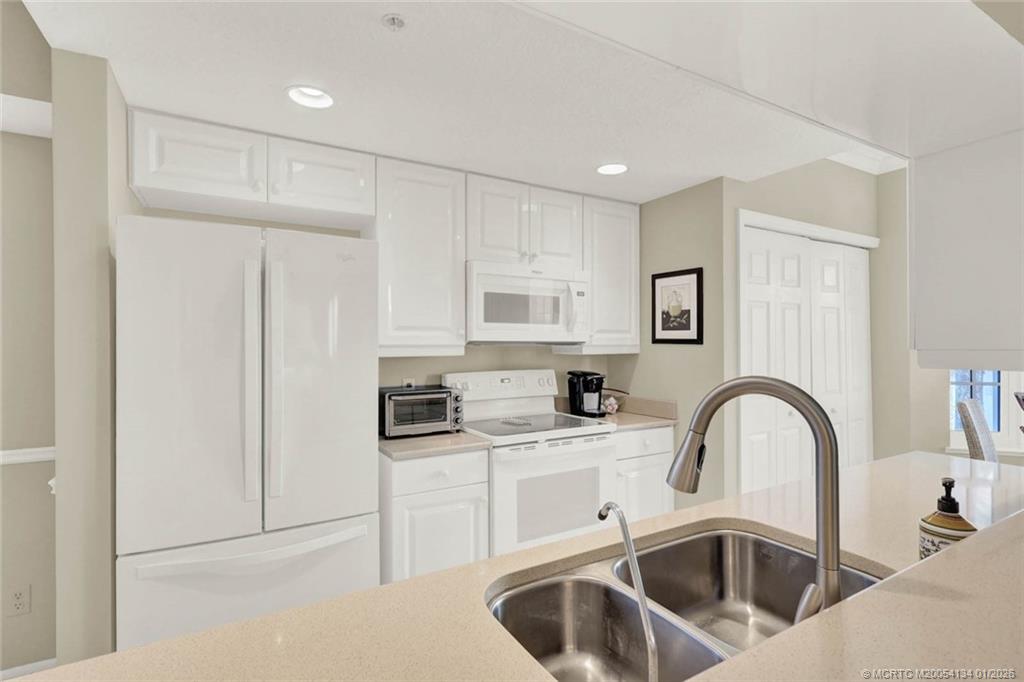 5700 Northeast Island Cove Way, Unit 4301 Stuart, FL 34996 - Photo 20 of 45 a kitchen with white cabinets a sink and appliances