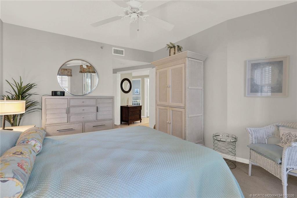 5700 Northeast Island Cove Way, Unit 4301 Stuart, FL 34996 - Photo 31 of 45 a spacious bedroom with a bed and a chandelier