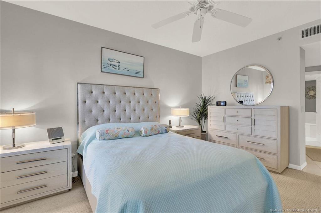5700 Northeast Island Cove Way, Unit 4301 Stuart, FL 34996 - Photo 32 of 45 a bedroom with a bed and a chandelier