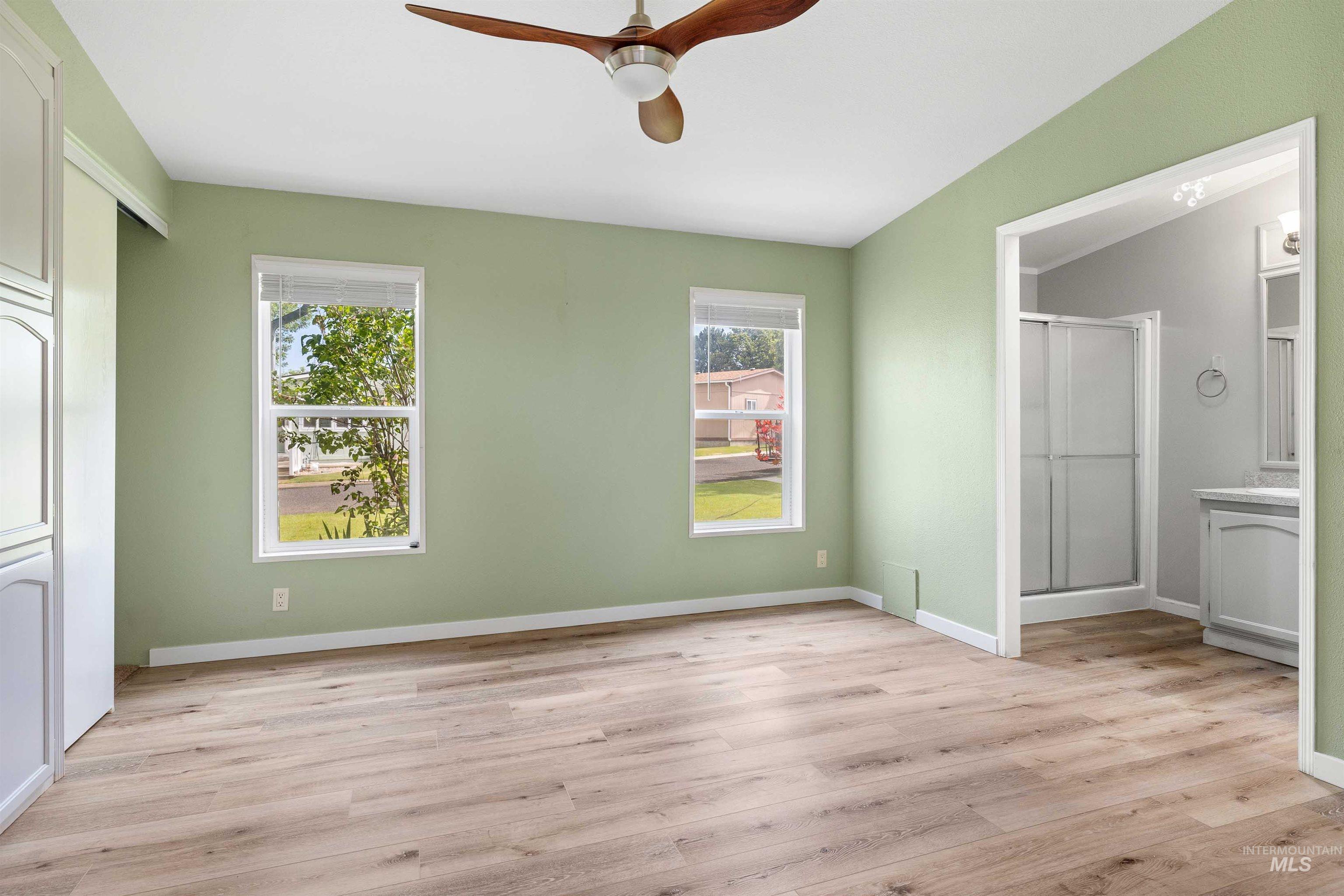910 Moonglo, Unit 80 Buhl, ID 83316 - Photo 12 of 25 Bedroom featuring wood-finish flooring, two large windows, a ceiling fan, and built-in cabinetry