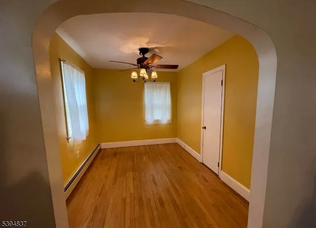 a view of an empty room with window and wooden floor