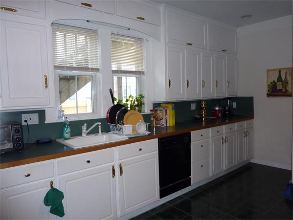 a kitchen with granite countertop white cabinets white appliances and a window