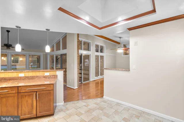 a view of an empty room with wooden floor and a ceiling fan