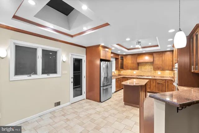 a large kitchen with stainless steel appliances kitchen island granite countertop a large counter top and view of living room