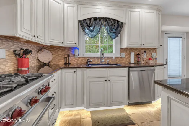 a kitchen with stainless steel appliances a sink a stove and white cabinets