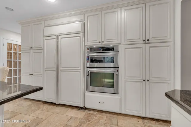 a kitchen with white cabinets and refrigerator