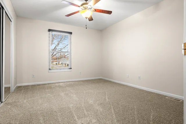 an empty room with windows and fan