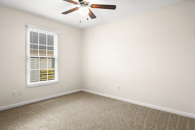 an empty room with a window and a fan