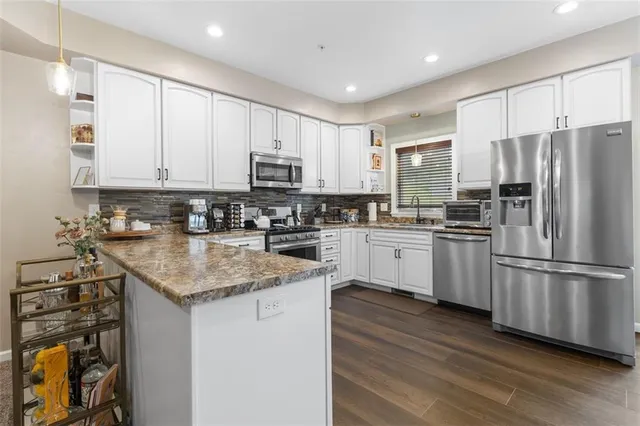 a kitchen with granite countertop white cabinets and white appliances