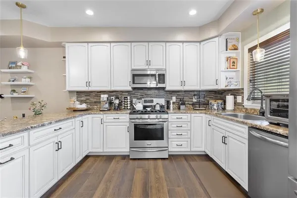 a kitchen with stainless steel appliances granite countertop a stove and white cabinets