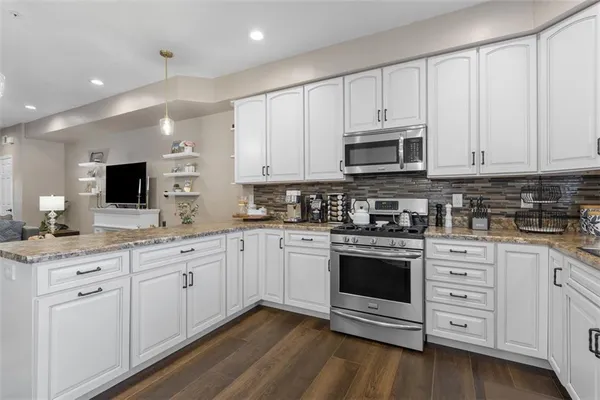 a kitchen with stainless steel appliances granite countertop a refrigerator sink and stove