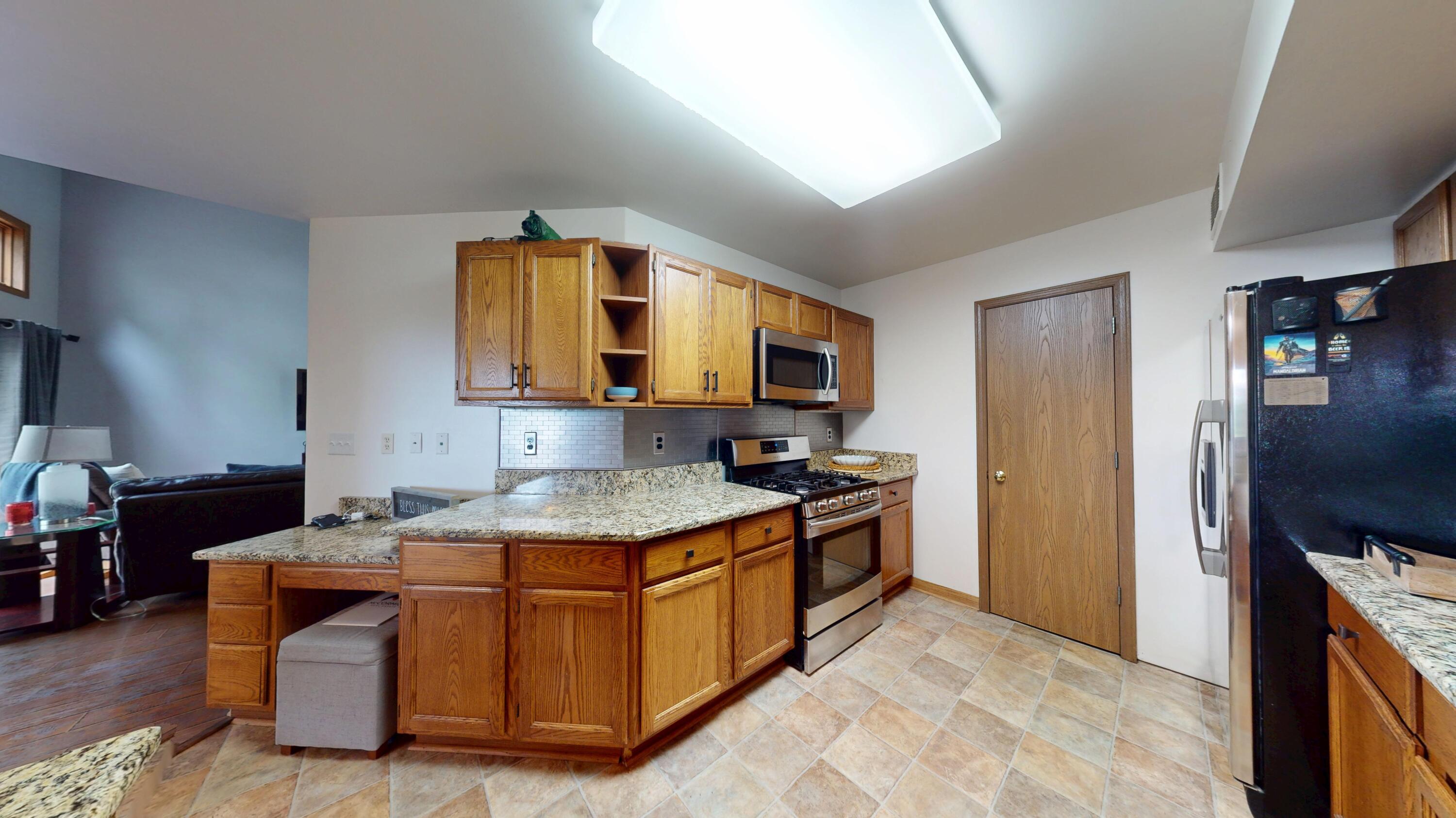 9344 Van Buren Street Crown Point, IN 46307 - Photo 11 of 37 a kitchen with stainless steel appliances granite countertop a stove a sink and a refrigerator
