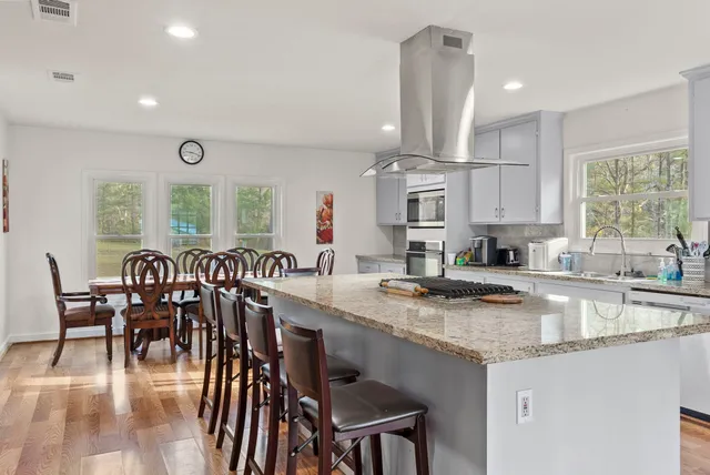 a kitchen with stainless steel appliances granite countertop a stove a sink a microwave a dining table and chairs